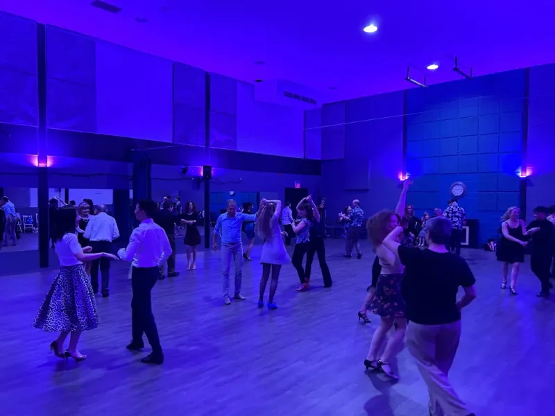 Couples filling the floor under blue lighting at a social dance party in Ottawa at DQ Ballroom & Fitness